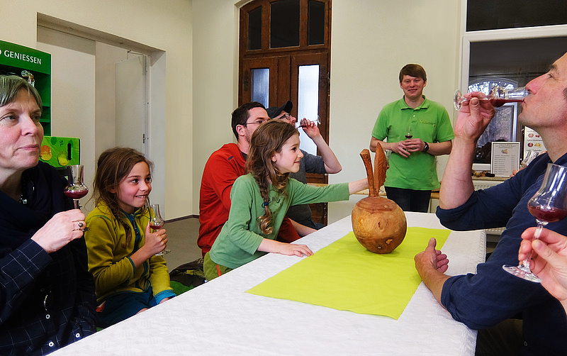 Das Bild zeigt Mitarbeiter des Atelier Papenfuss und Kinder beim Verkosten von Obstsaft in der Kelterei im Bahnhof Donndorf