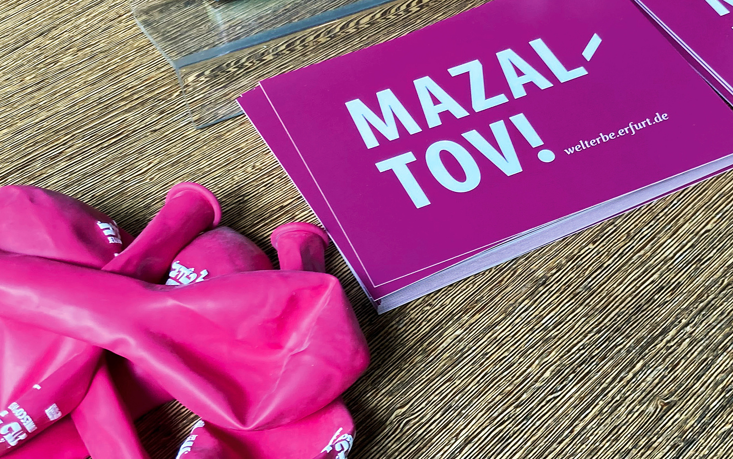 Das Bild zeigt eine Postkarte mit "Mazal Tov!" und farbig passenden Luftballons zur Kampagne. (© Papenfuss | Atelier)
