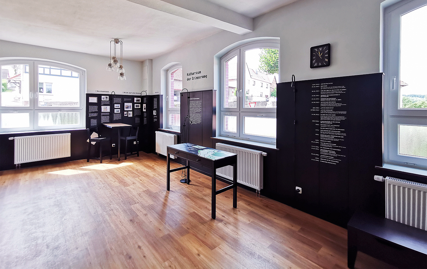 Kulturraum der Erinnerung Glasehausen Gaststube Ausstattung Das Bild zeigt den Blick auf einen Teil der Gaststube. Die Details wie die Lampen und die Uhr sind gut zu sehen. (© Papenfuss | Atelier)