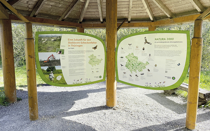 Das Bild zeigt den Pavillon entlang des Rundweges Wilde Weide mit den Tafeln zum Scheckenfalter und Natura 2000.