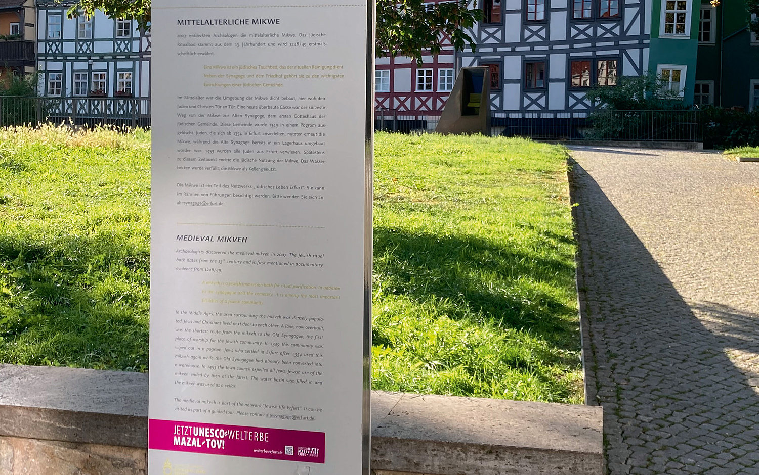 Kampagne Mazal Tov Erfurt UNESCO Welterbe Stele Mikwe Das Bild zeigt die Informationsstele an der Mittelalterlichen Mikwe in Erfurt. Sie wurde mit einem Aufkleber des Kampagnenmotivs versehen. (© Papenfuss | Atelier)
