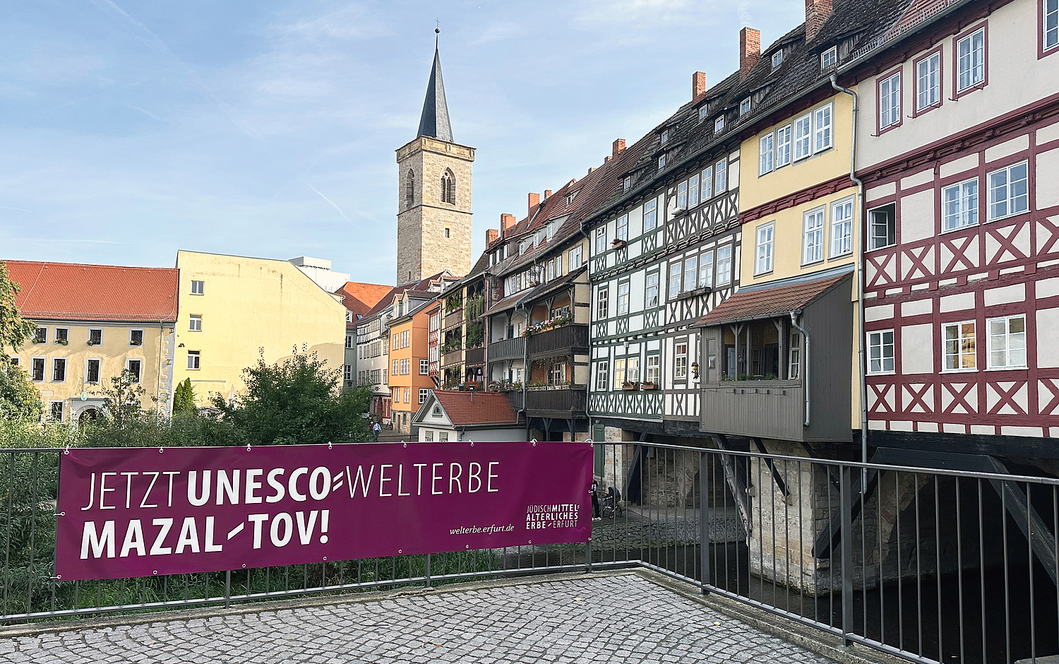 Kampagne Mazal Tov Erfurt UNESCO Welterbe Banner Mikwe Das Bild zeigt ein Banner mit dem Kampagnenmotiv an der Mikwe in Erfurt. (© Papenfuss | Atelier)